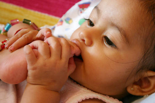 a cute baby girl biting her toes